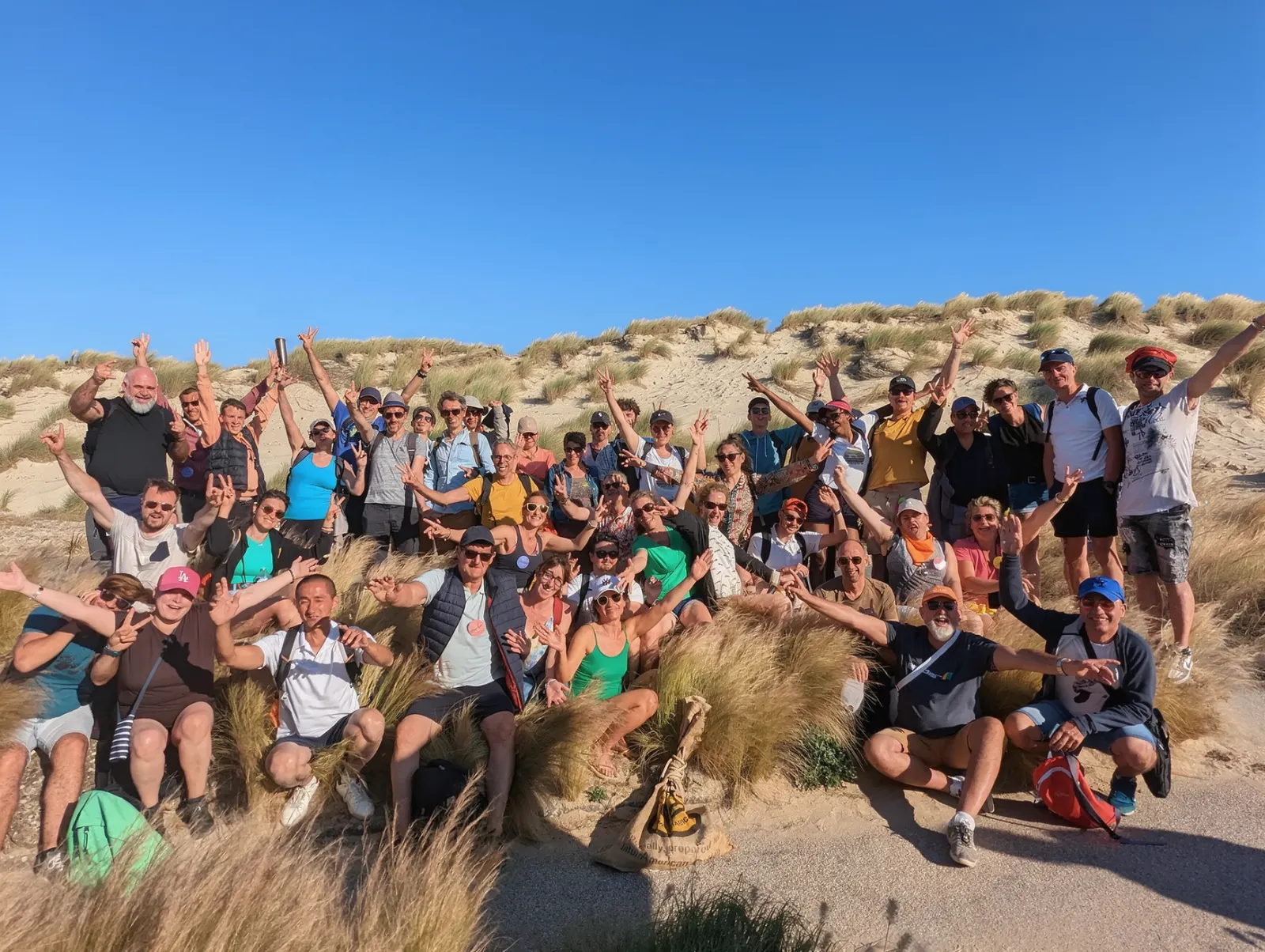 L’équipe SIB réunie en extérieur, bras levés et sourires, devant des maisons de bord de mer.