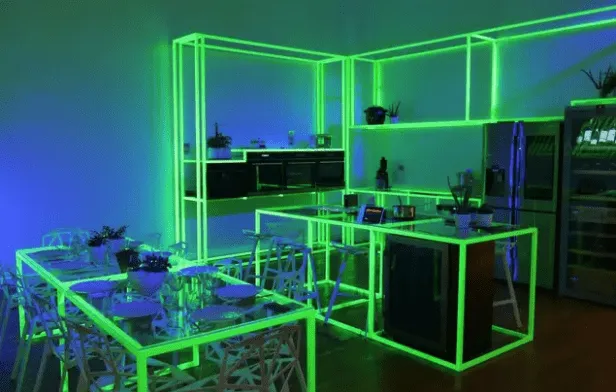 Cuisine équipée mise en scène dans un espace de démonstration, soulignée de néons verts