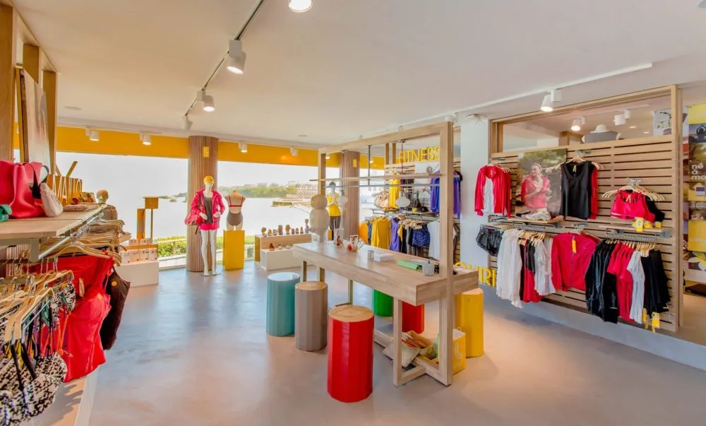 Point de vente textile : magasin de vêtements de sport aux portants en bois, ouvert sur la mer