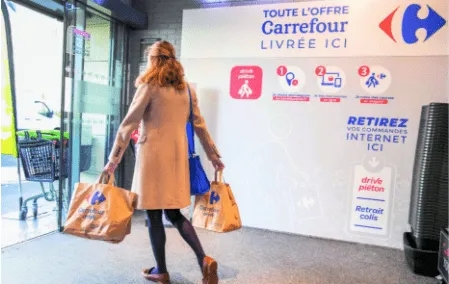 Drive piéton Carrefour : cliente sortant du point de retrait, sacs en main